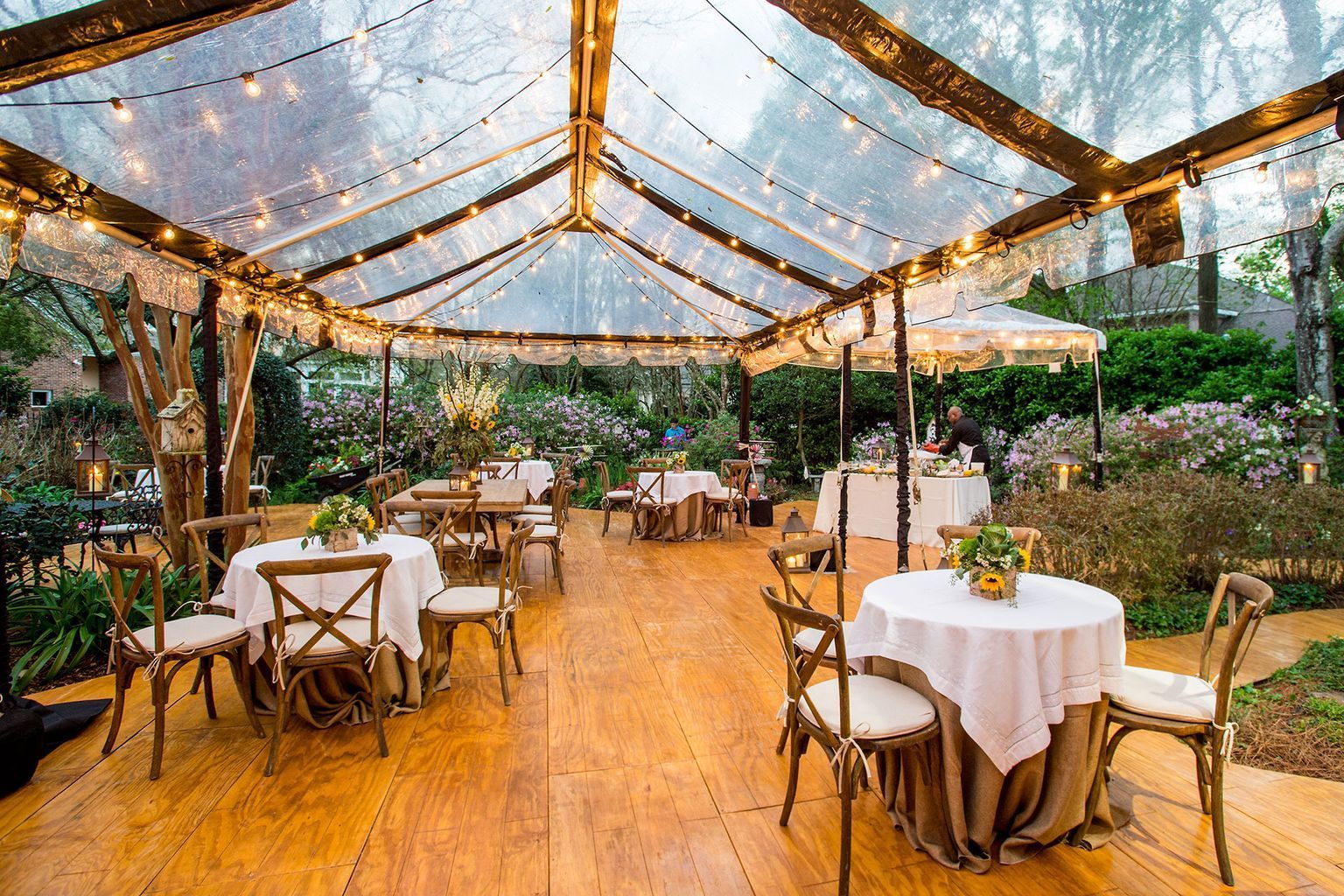 There are tables and chairs under a clear tent.