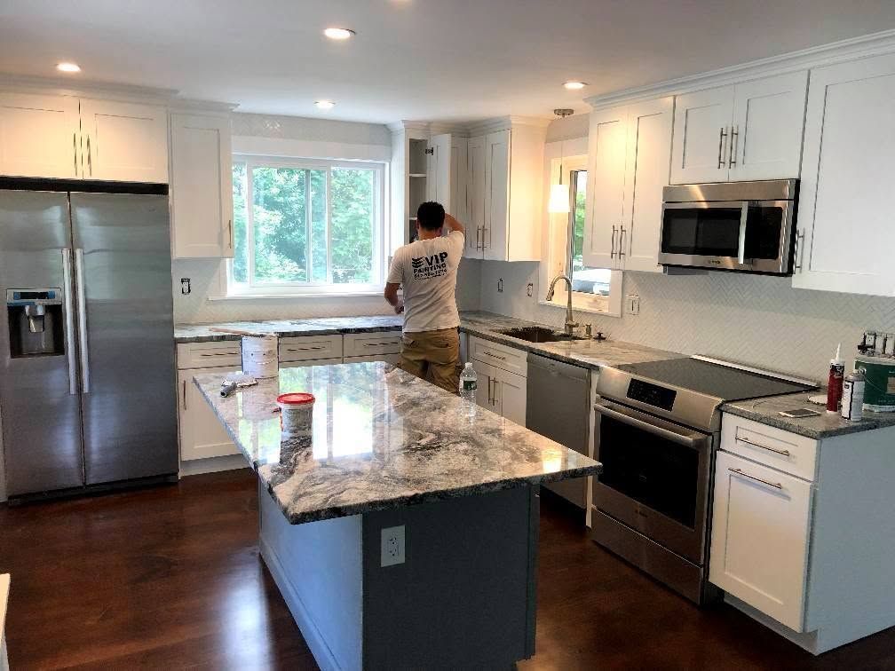 Modern kitchen with stainless steel appliances and a person standing by the window.