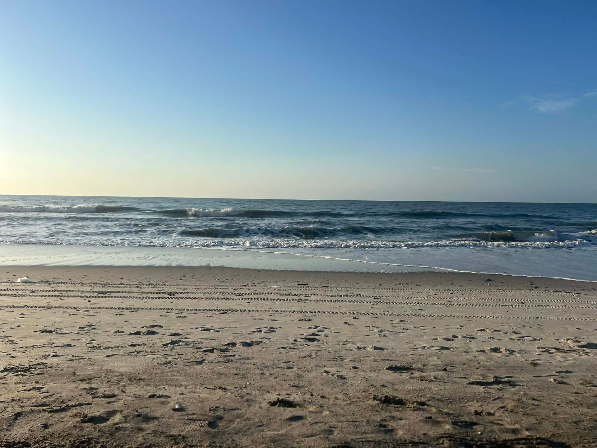 Sunny beach with gentle waves and clear blue sky