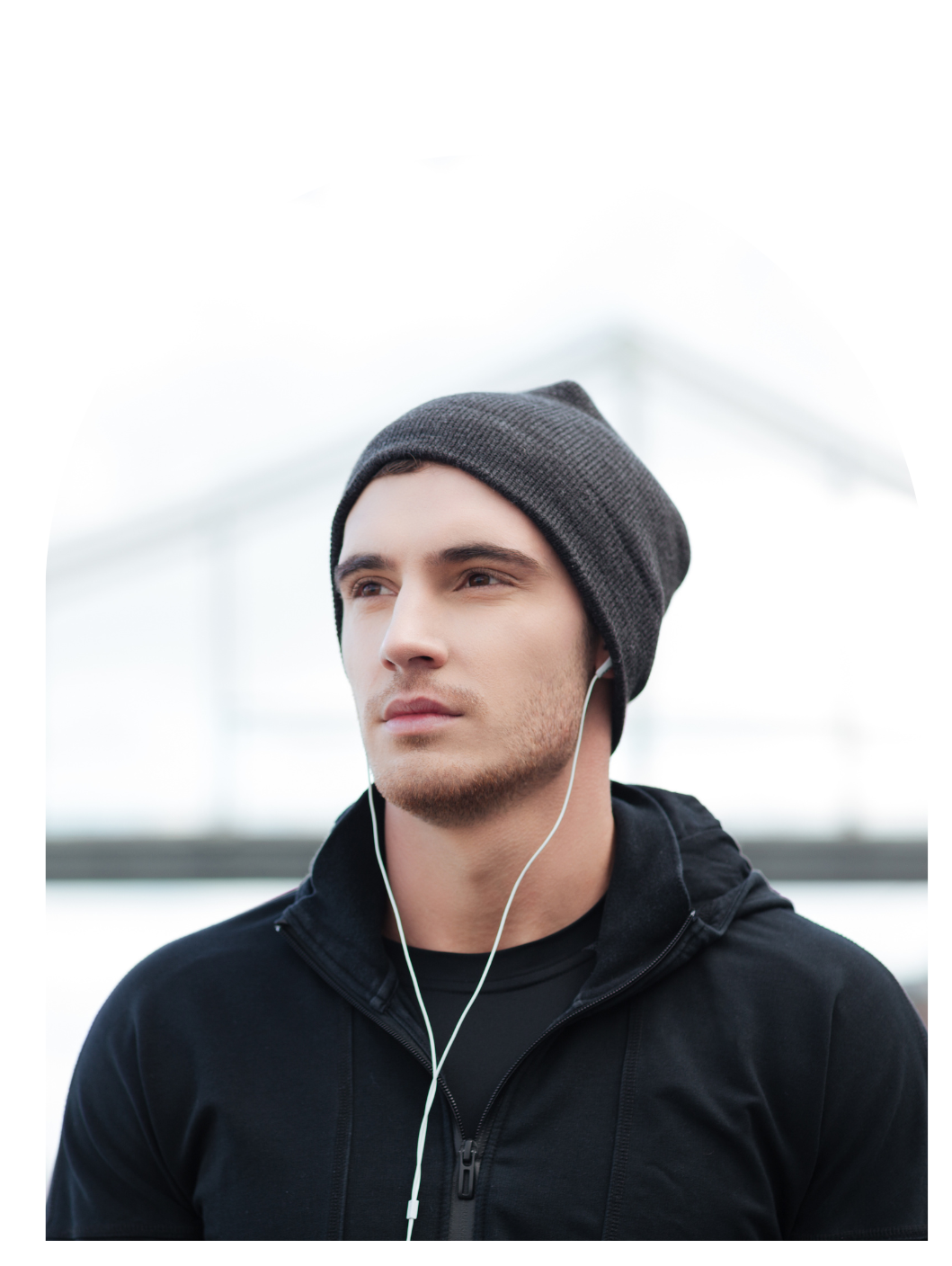 A man wearing a beanie and headphones looks to the side