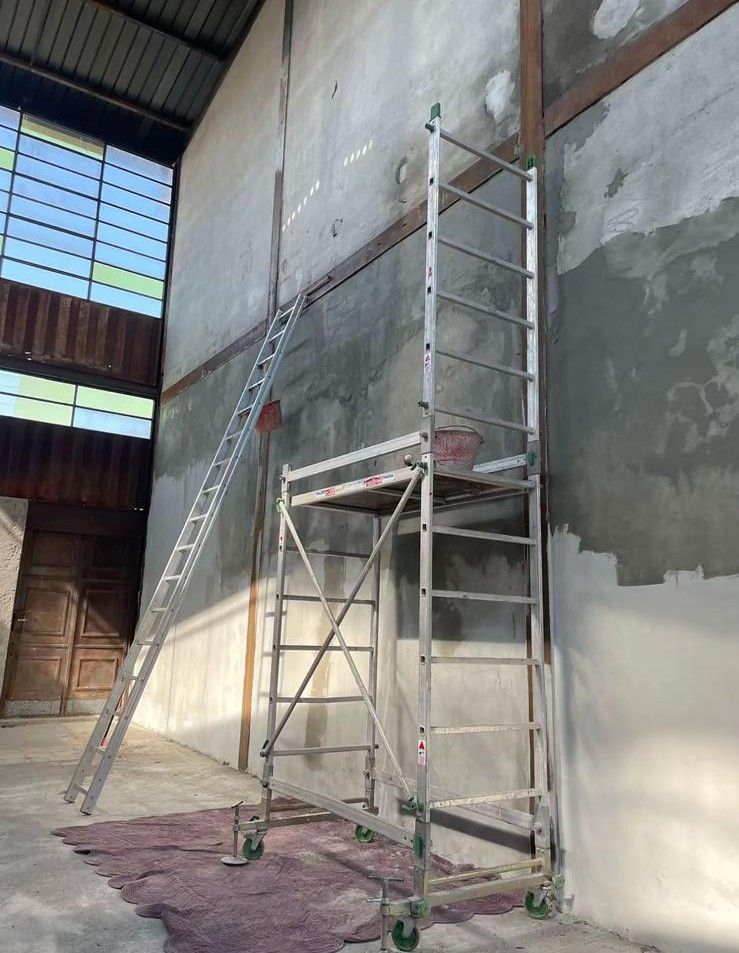 Ponteggi e scale addossati a un'alta parete interna in costruzione