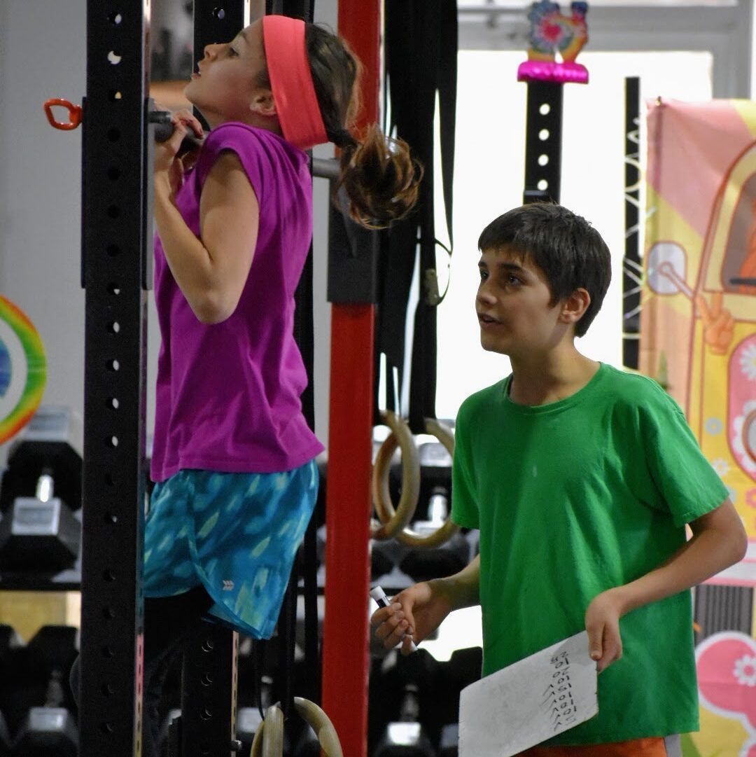 A boy in a green shirt stands next to a girl in a purple shirt
