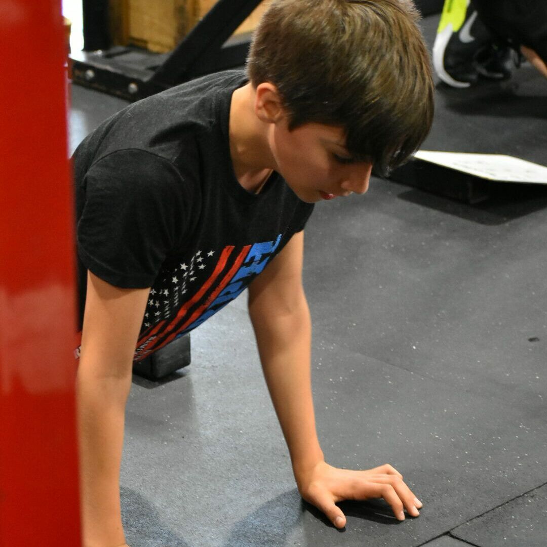 A young boy is doing push ups in a gym
