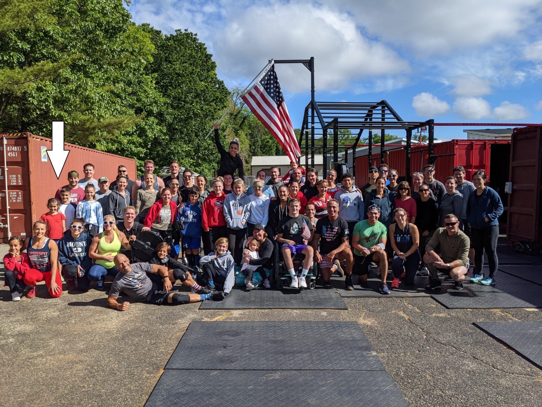 A large group of people are posing for a picture in front of an american flag.