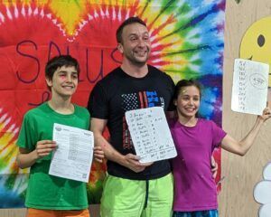 A man and two children are standing next to each other holding papers.