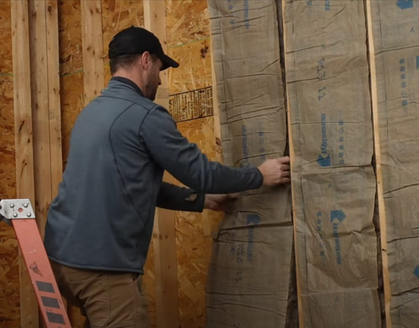 Crew member installing insulation in a garage.