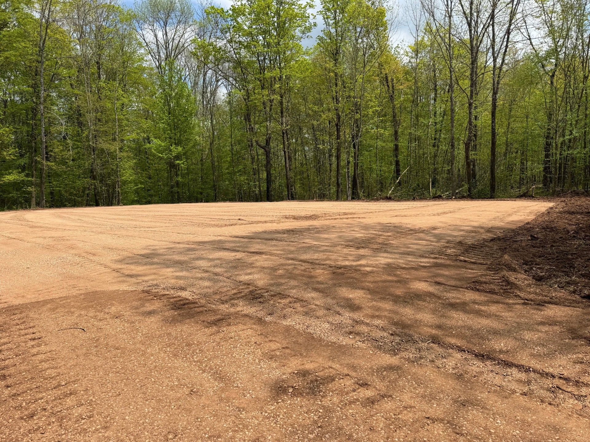 Level dirt lot near woods.