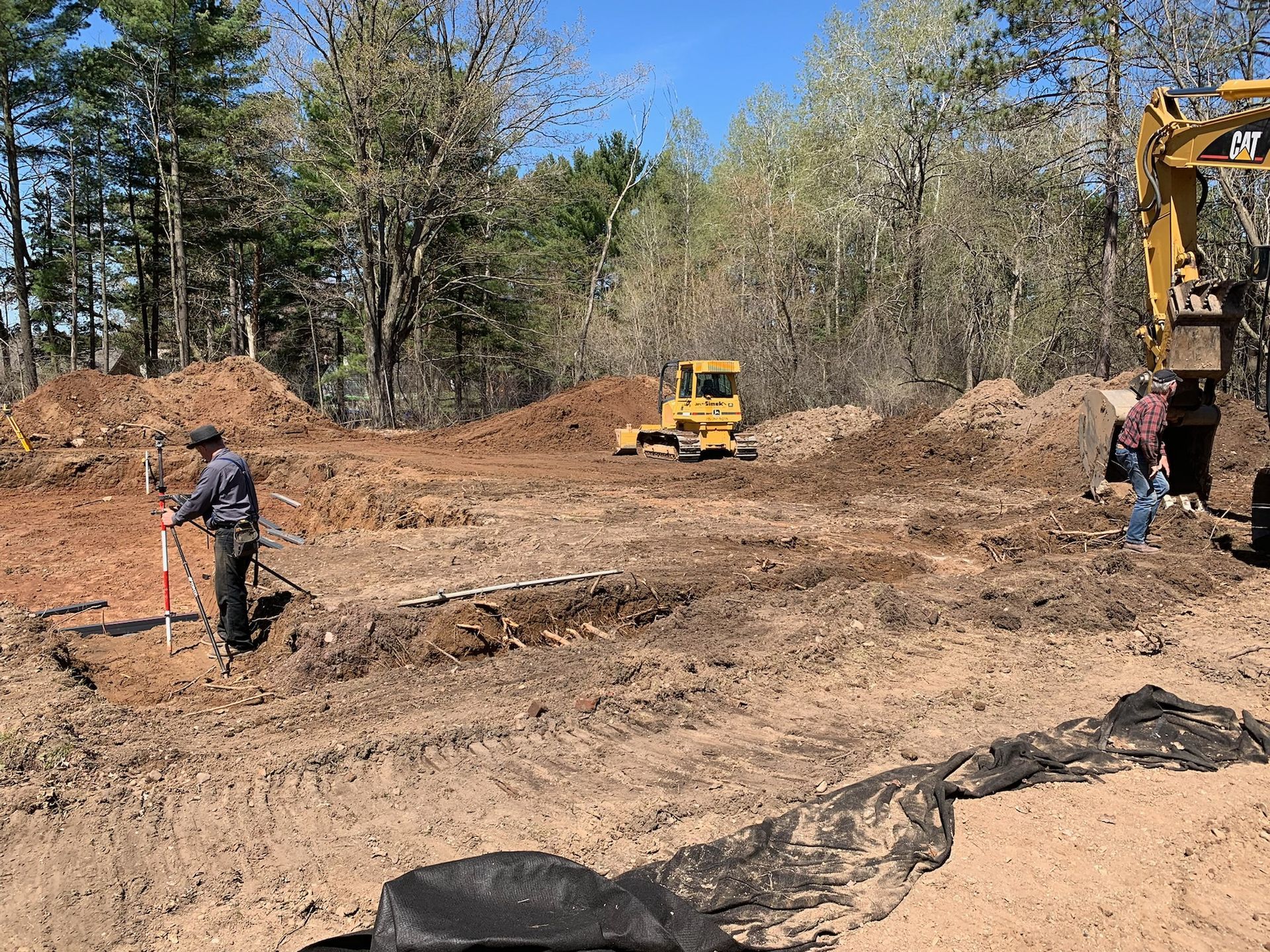 Construction site with earth-moving equipment and workers surveying the land.