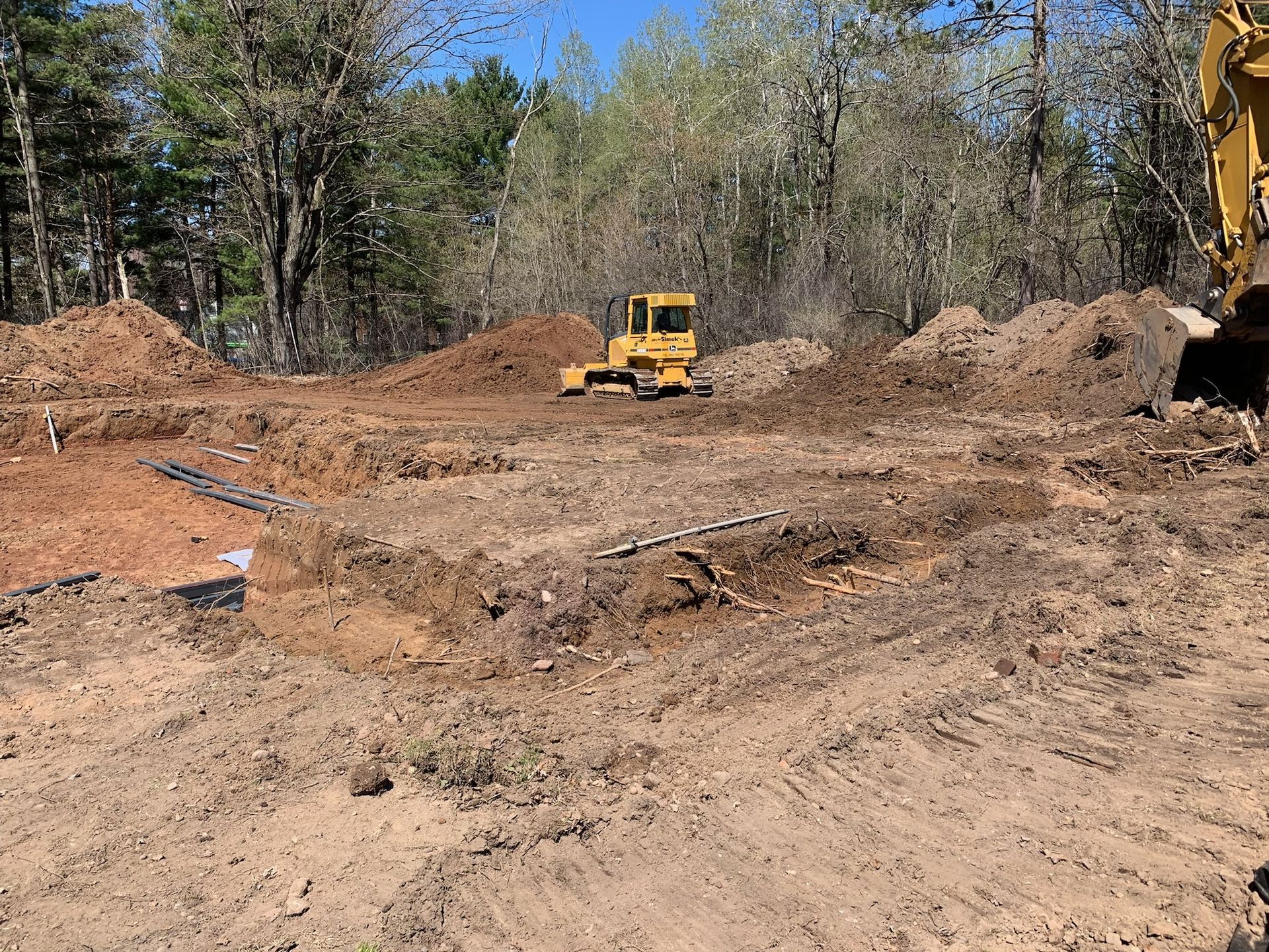 Construction site with yellow bulldozer, excavated earth, and dirt piles.