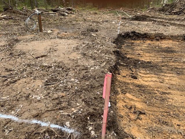 Dirt and cleared land with a pink marker and white line indicating construction.