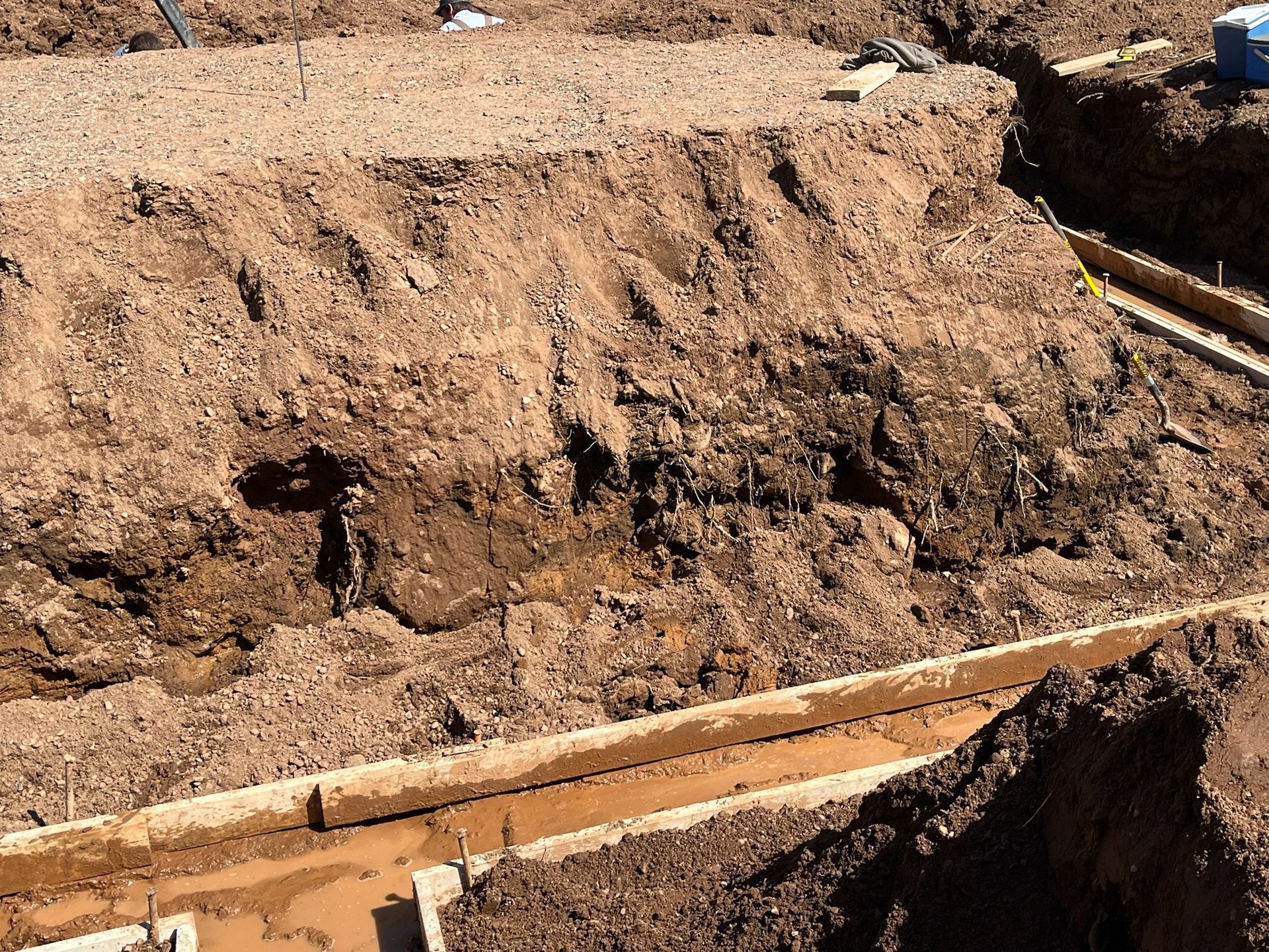 Construction site: earth and gravel pile next to wooden formwork for a foundation.