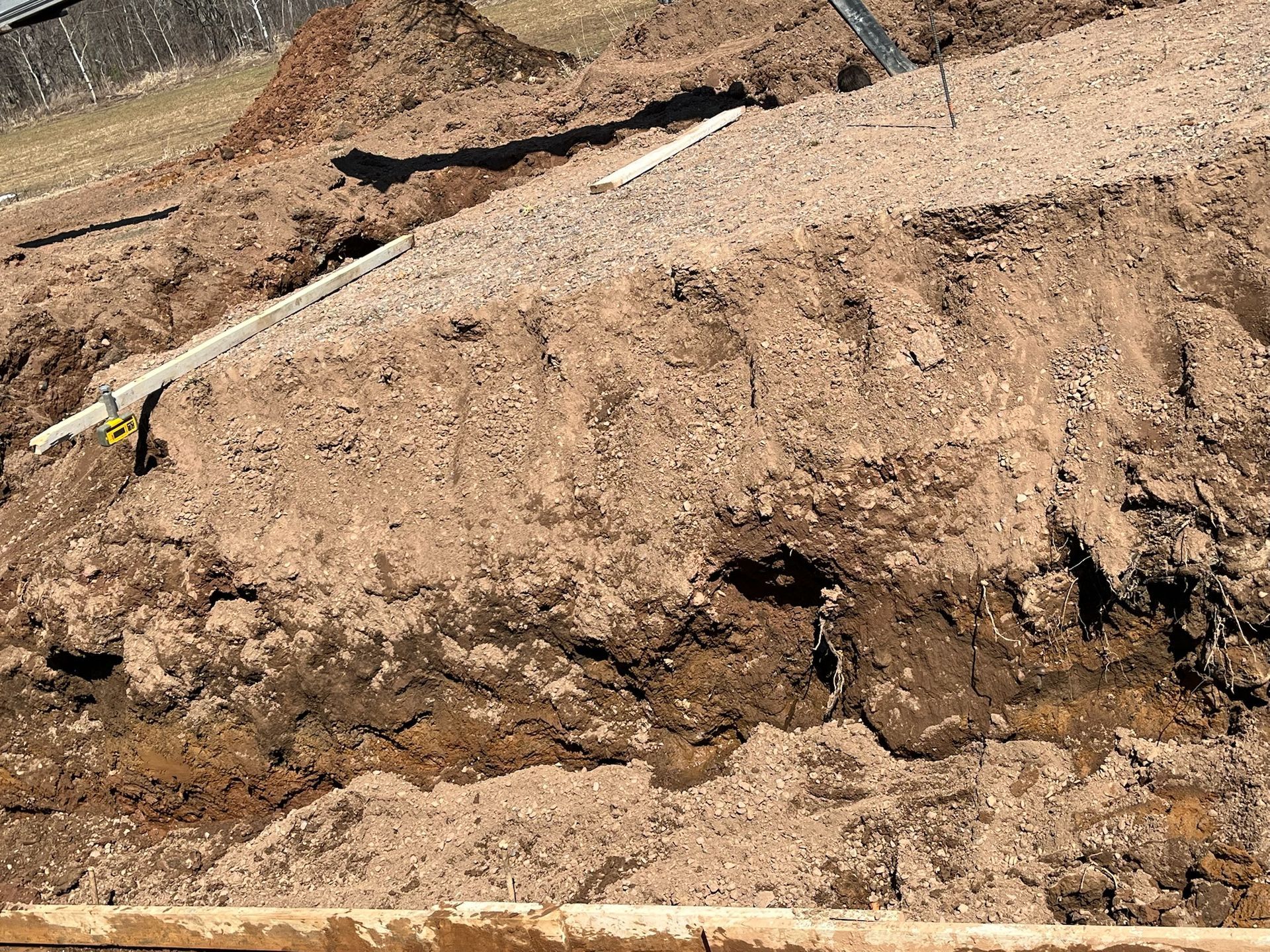 A pile of excavated dirt with a white level and wooden frame visible.