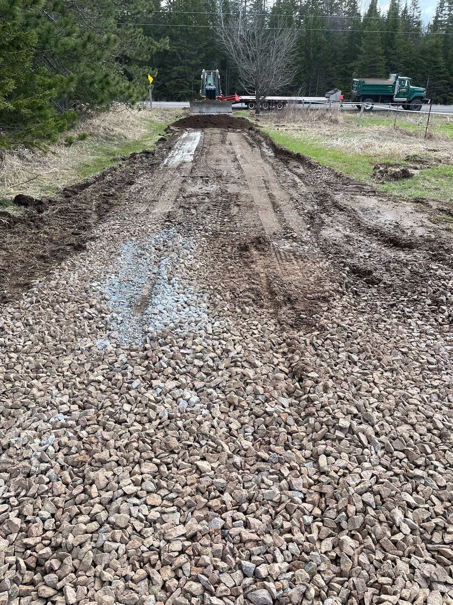 Gravel road under construction. Truck and equipment in the background.