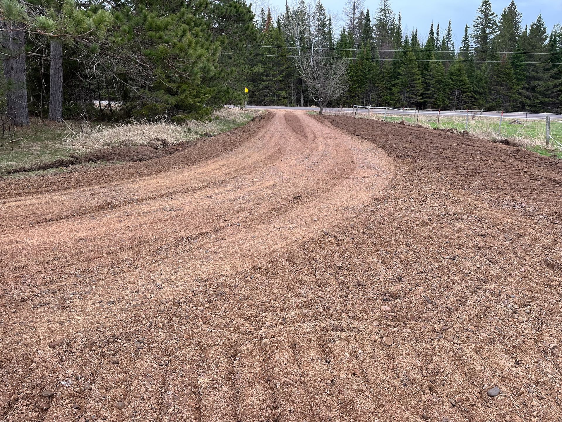 Curved dirt road through a wooded area with fresh wood chip covering.