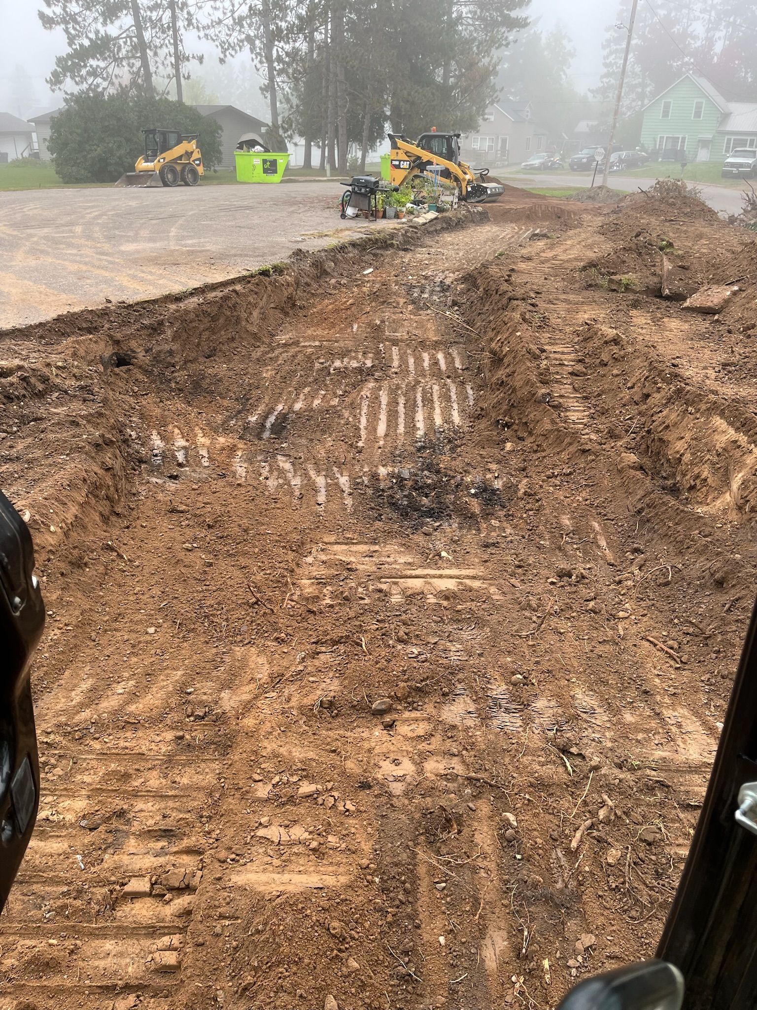 Construction site with earthmoving equipment and muddy ground.