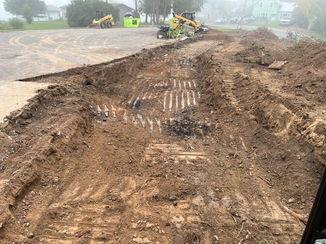 Construction site with excavators and freshly dug trench in a dirt lot.