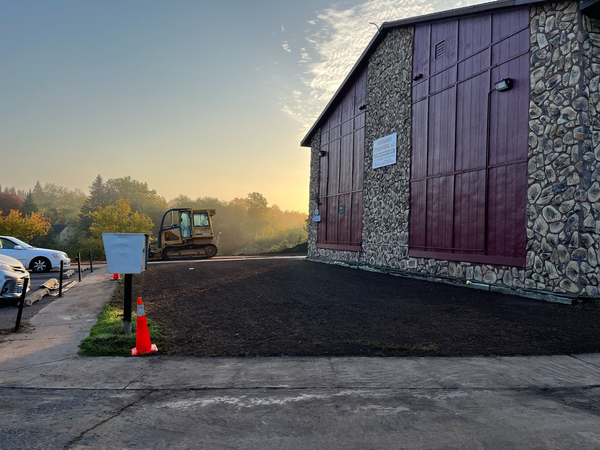 Building with burgundy doors and stone siding, construction in progress.