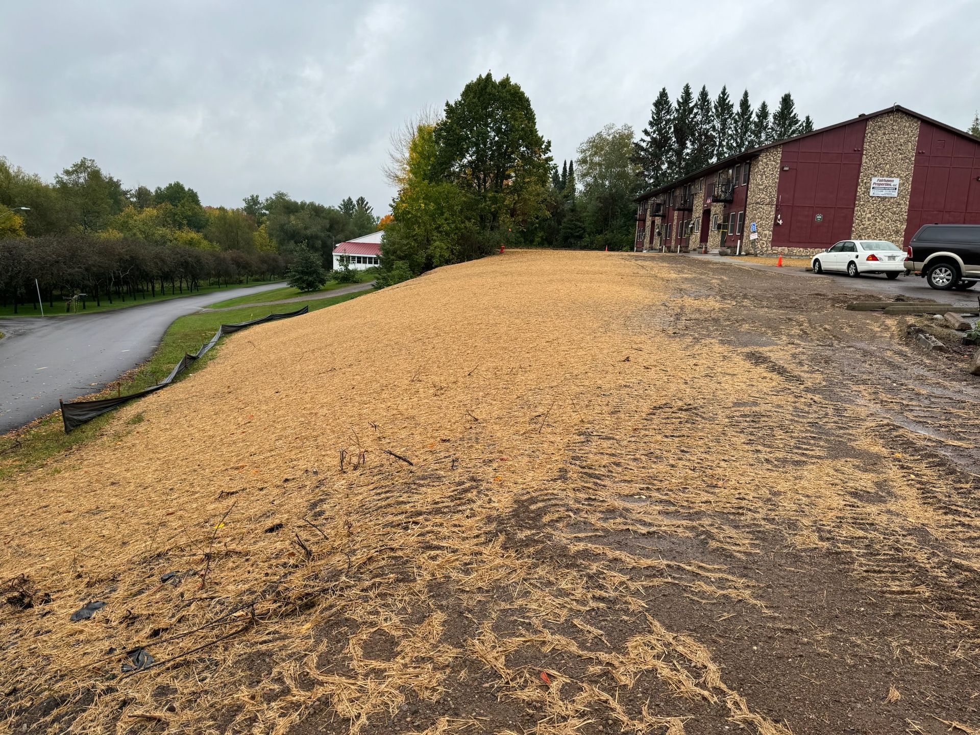 A sloped area covered in wood chips next to a building. Overcast sky.