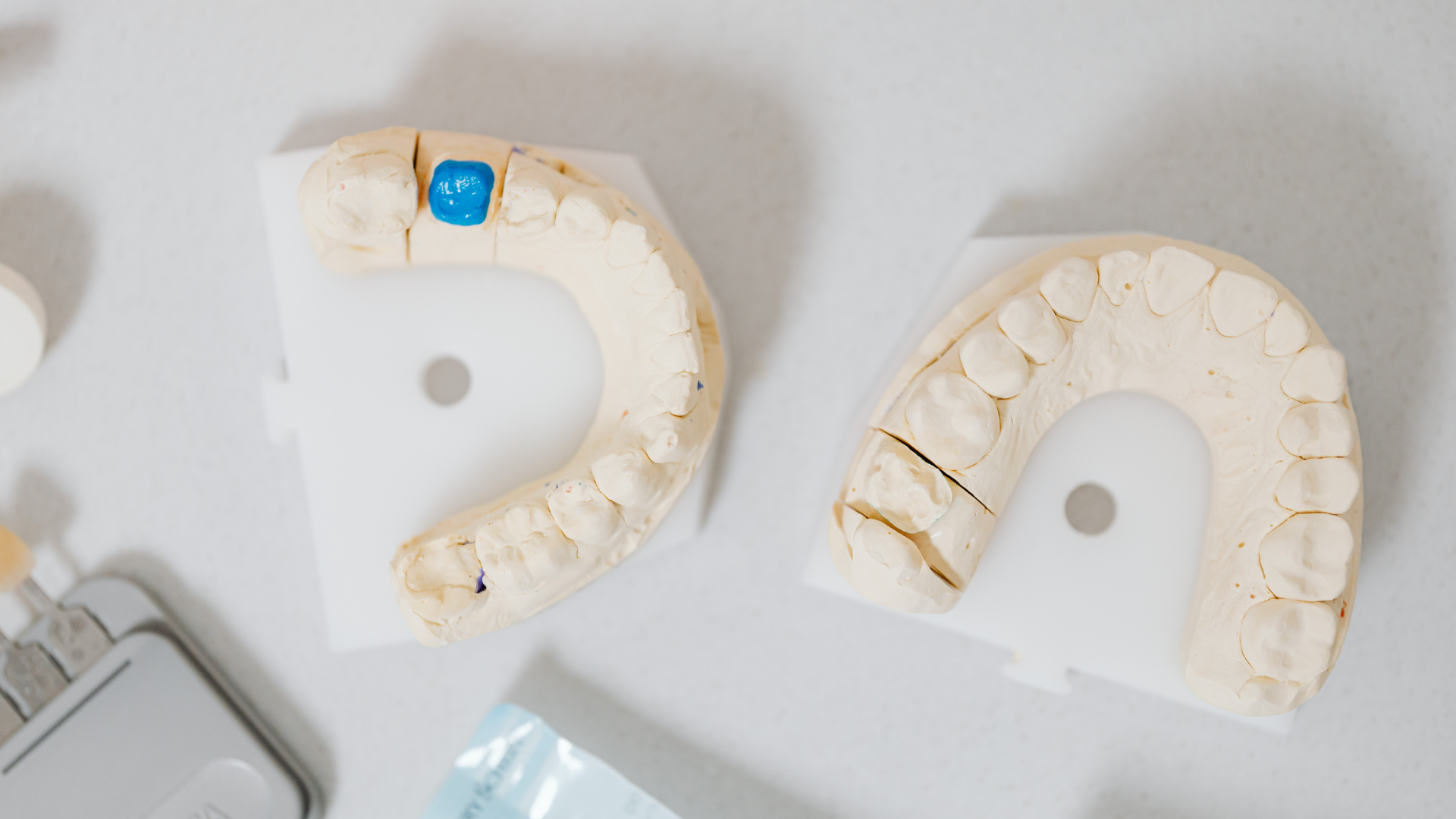 Two semicircular white objects with beige pieces on a light surface, one marked with a blue clip.