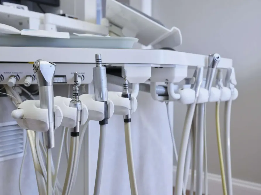 Dental treatment chair with multiple hanging instruments and hoses in a clinic