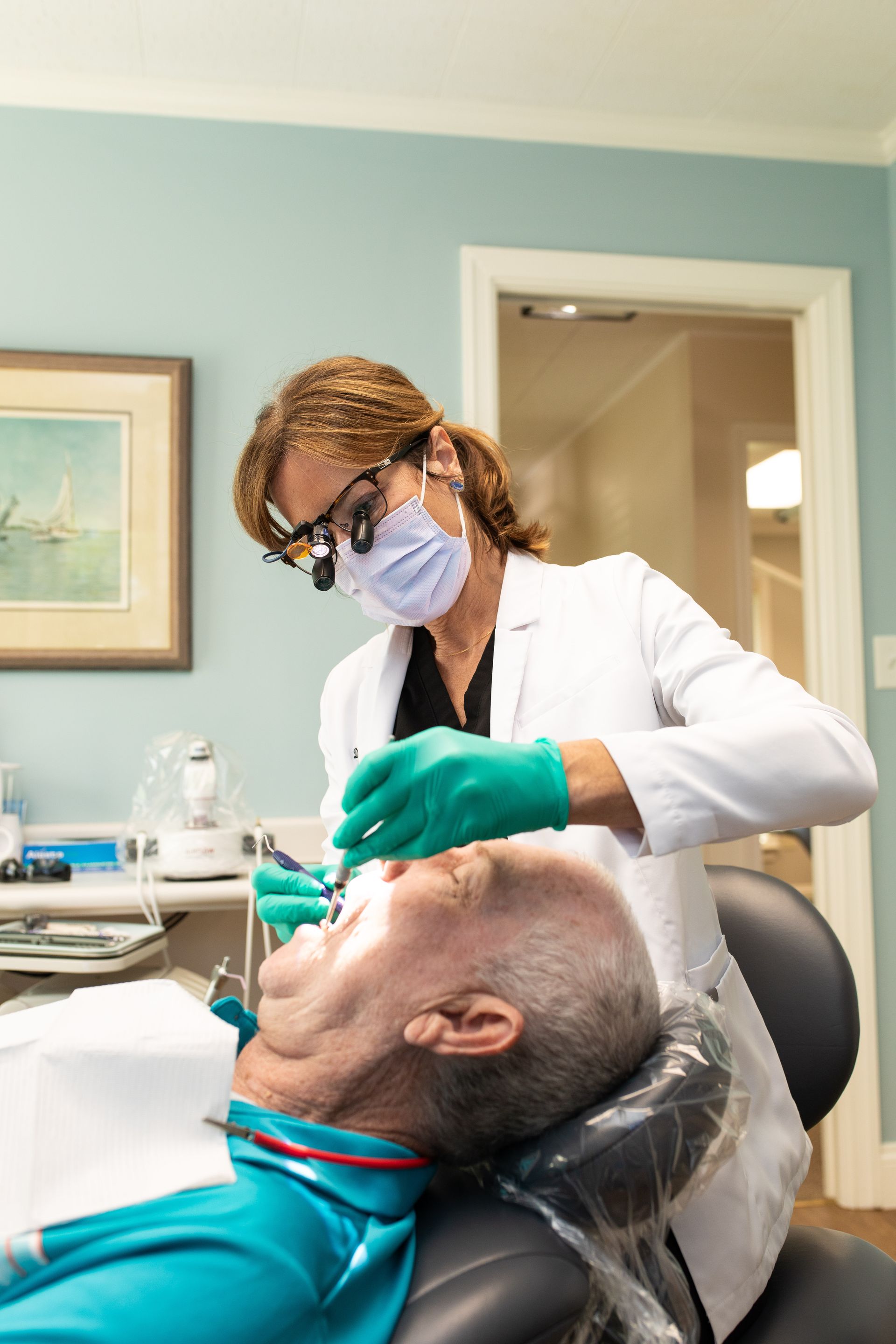 Gloved hands holding a dental model with teeth and braces in a clinic setting