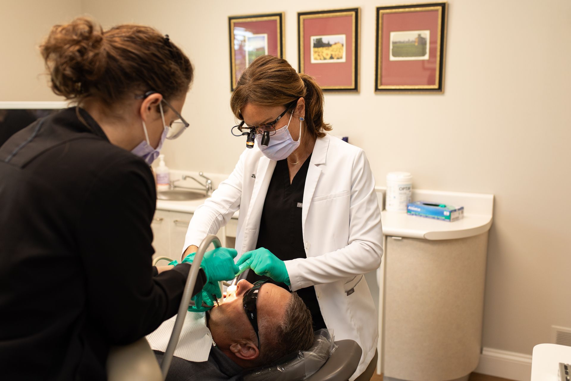 Dentist and assistant examine a patient in a dental chair at a clinic