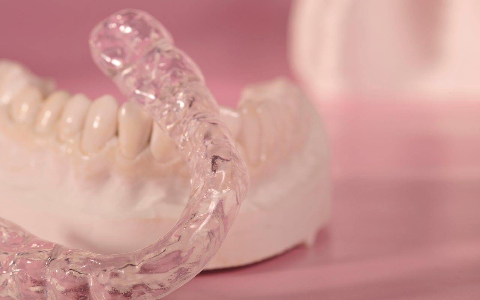 Hands holding clear dental aligners near a smiling mouth