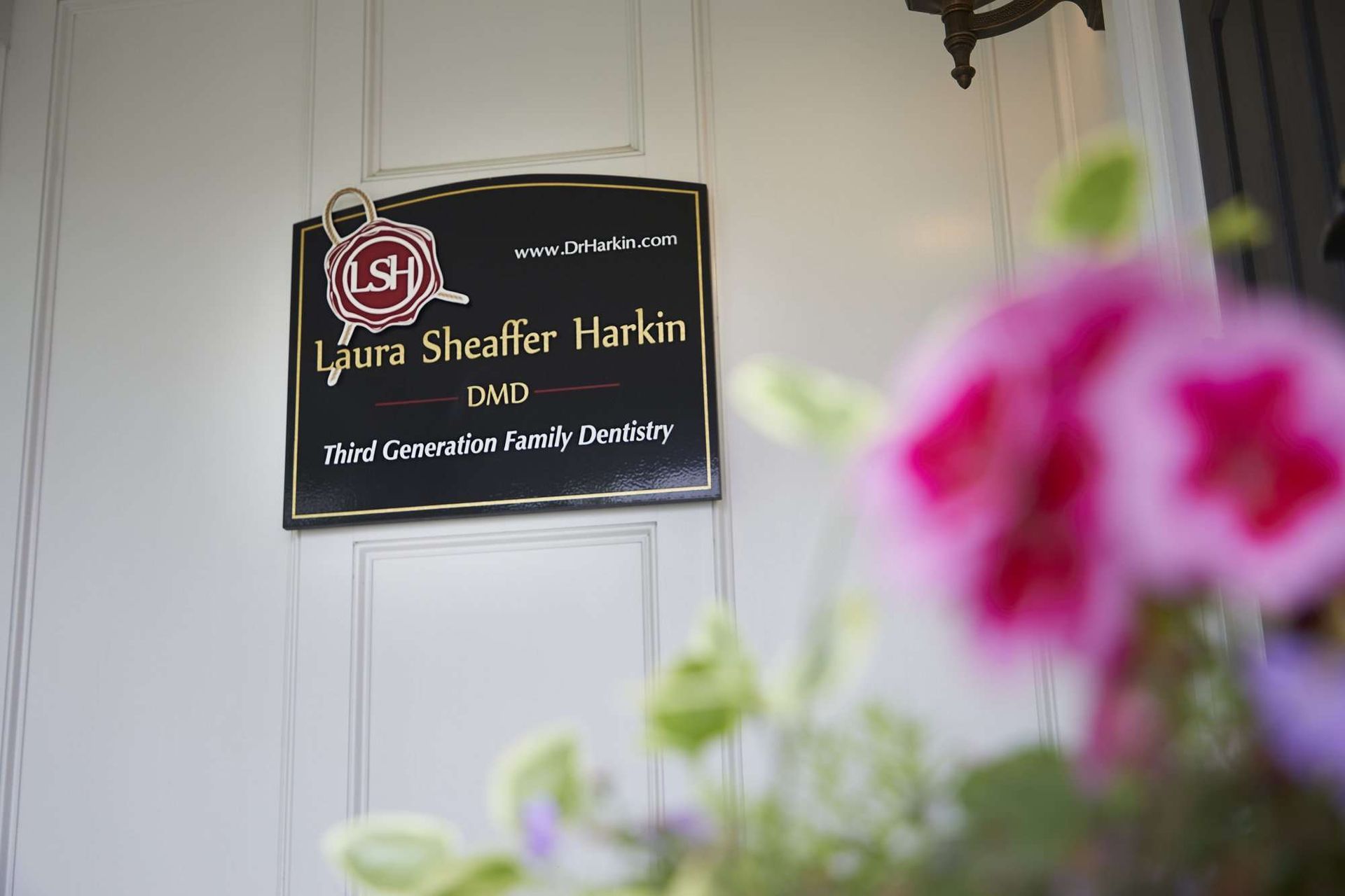 Sign for Sierra Shelter Home on a wall, blurred pink flowers in the foreground