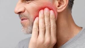 Man holding his cheek in pain, appearing to have a toothache.