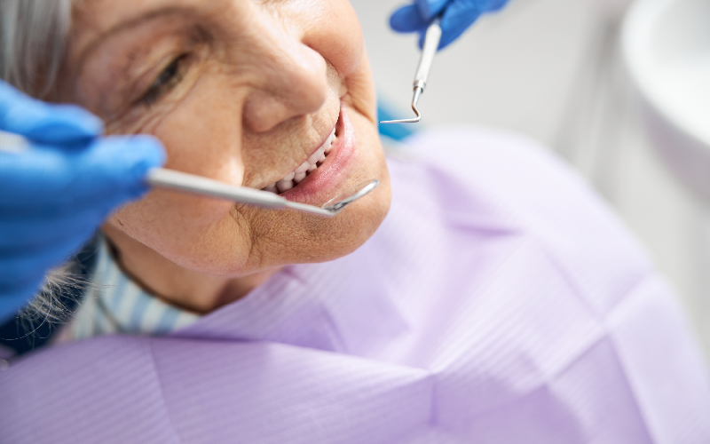 Dental checkup with a patient reclined in a chair while a dentist uses tools in a bright clinic