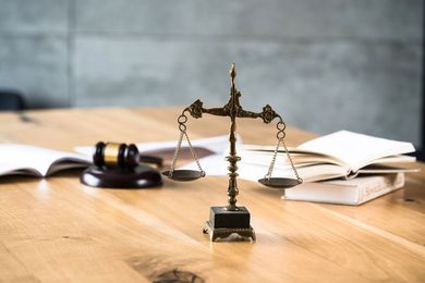 Sobre una mesa de madera hay una balanza de la justicia y un mazo de juez.