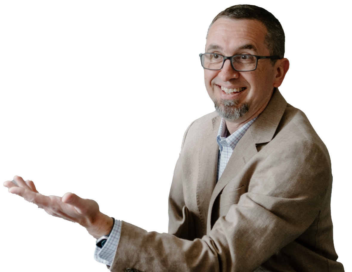 Lew Smith in a suit and glasses, is smiling and holding out his hands.