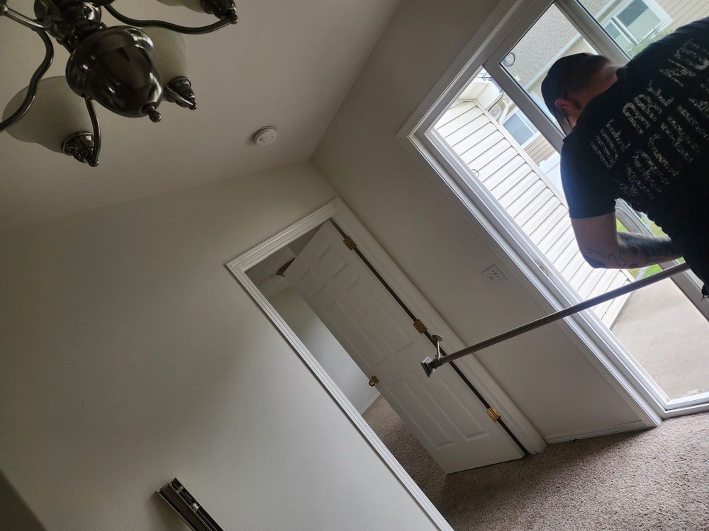 Person using a pole in a carpeted room near a window and closed door