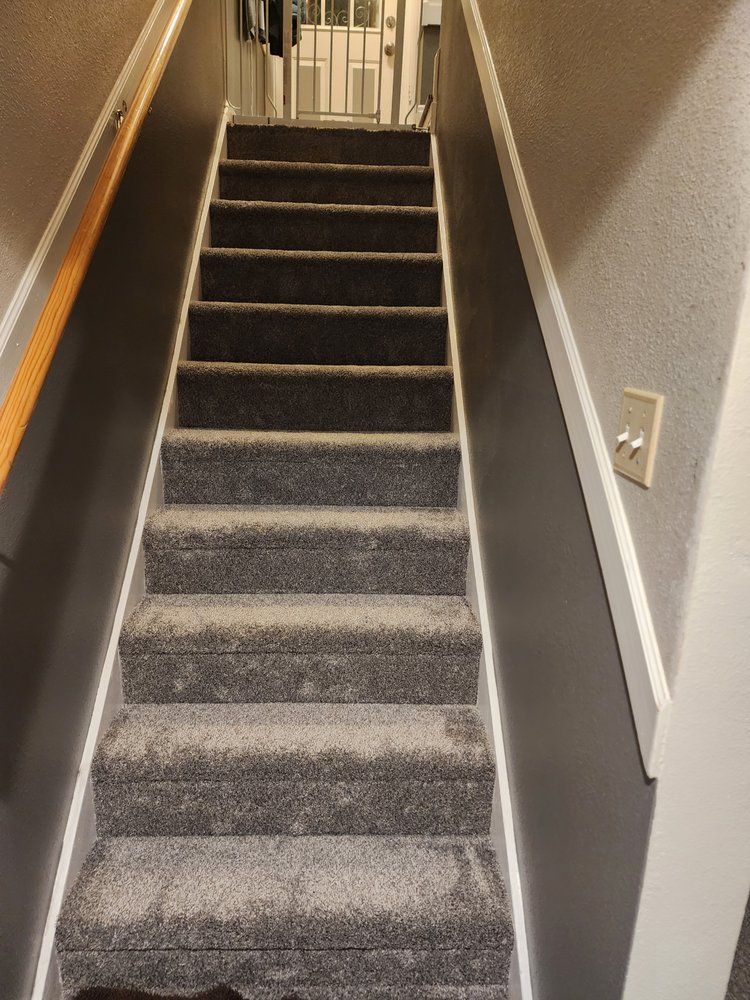 Narrow carpeted staircase with gray walls and white trim in a hallway