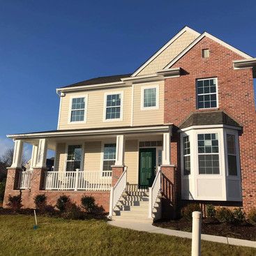 a large brick house with a large porch and stairs .