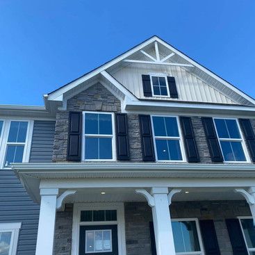 the front of a house with black shutters and a blue sky in the background .