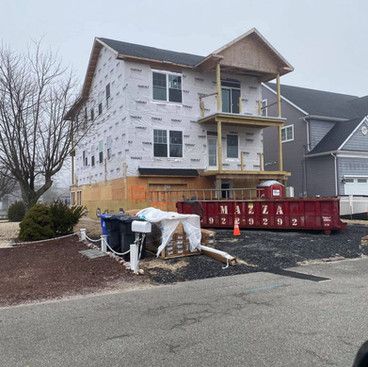 a house is being built in a neighborhood with a dumpster in front of it .