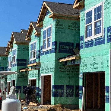 a row of houses are being built with green insulation .