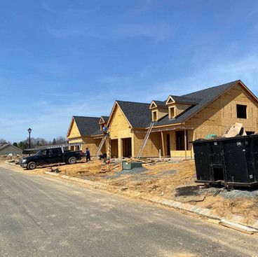 a row of houses are being built on the side of a road .