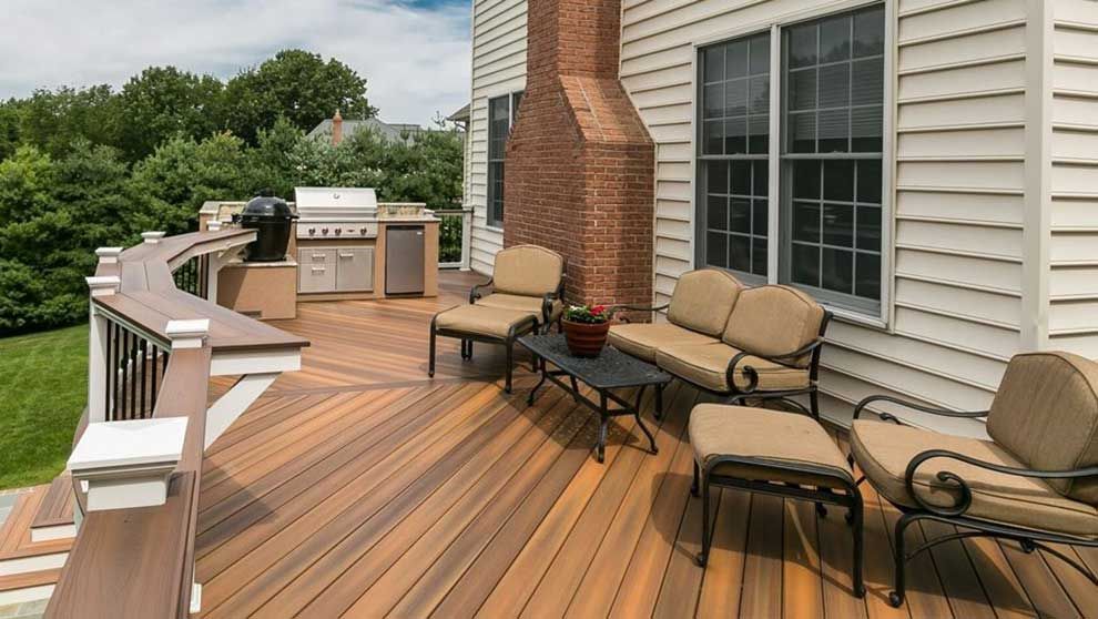 a wooden deck with a couch , chairs , table and grill .