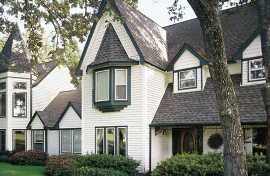 a white house with a black roof and a bay window