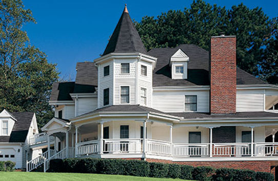 a large white house with a large porch and a brick chimney .
