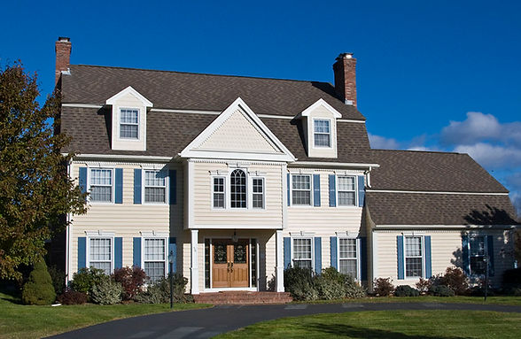 a large white house with a brown roof and blue shutters