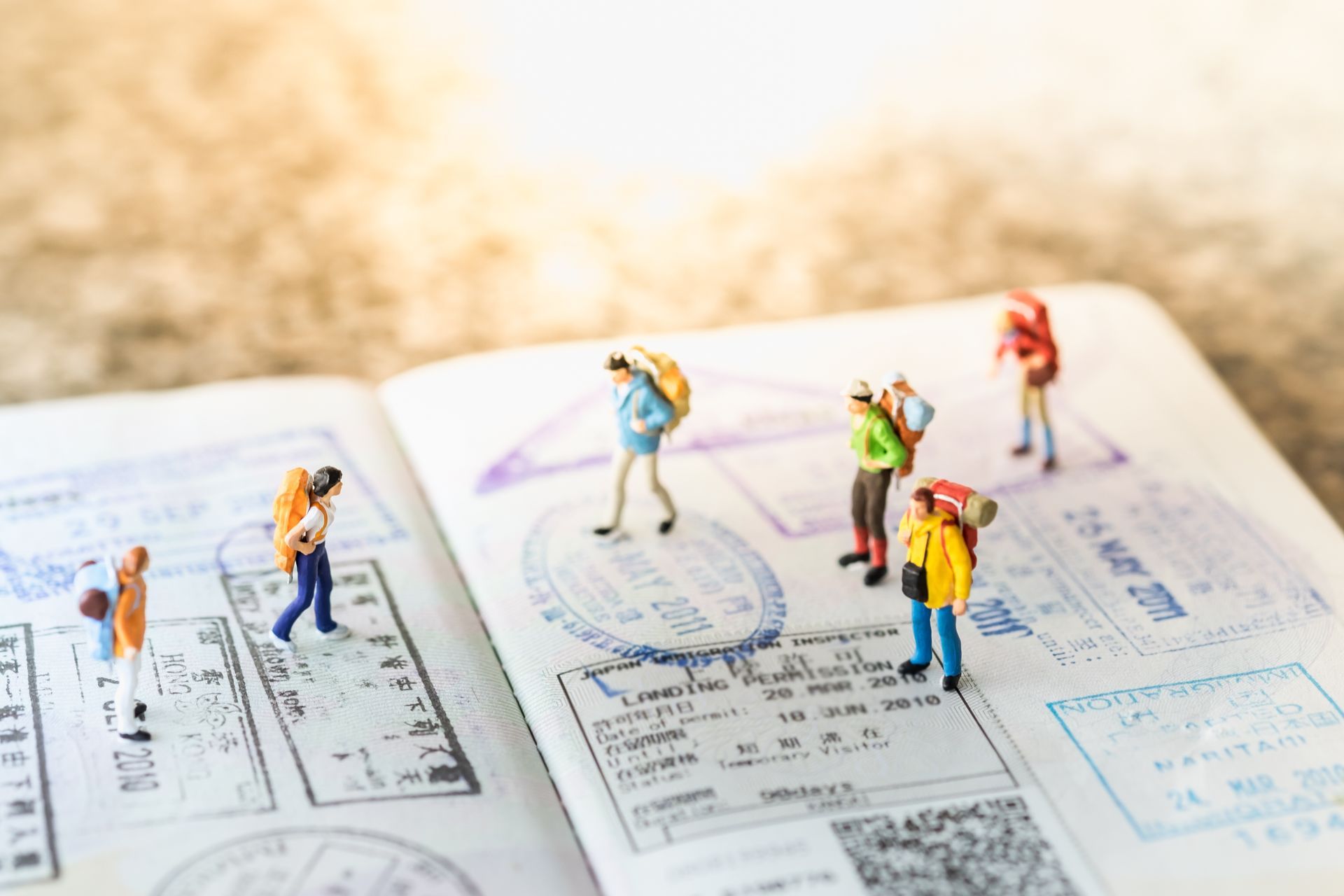 Miniature hikers standing on an open book with maps and diagrams in the background