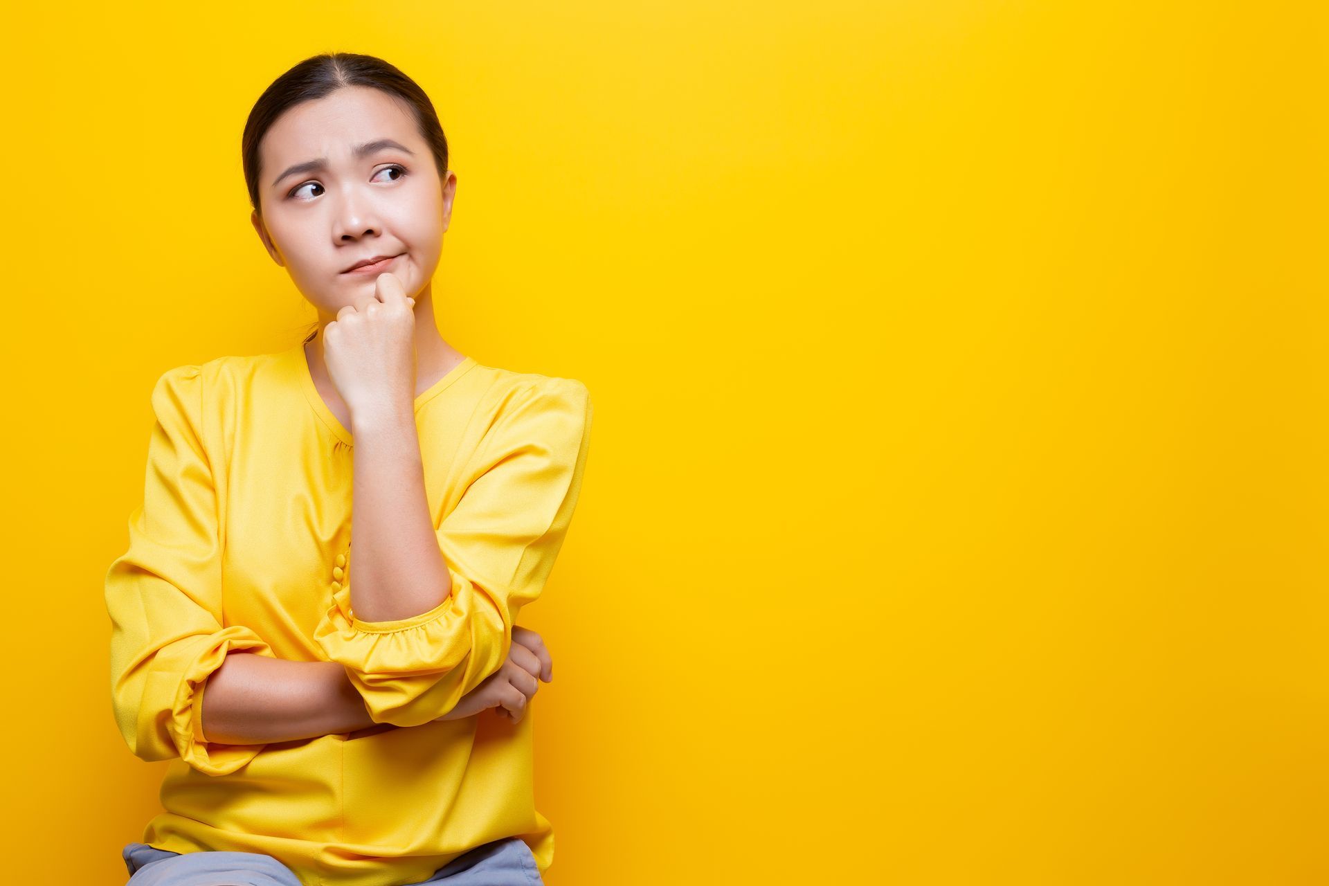 Person in a yellow shirt thinking against a bright yellow background