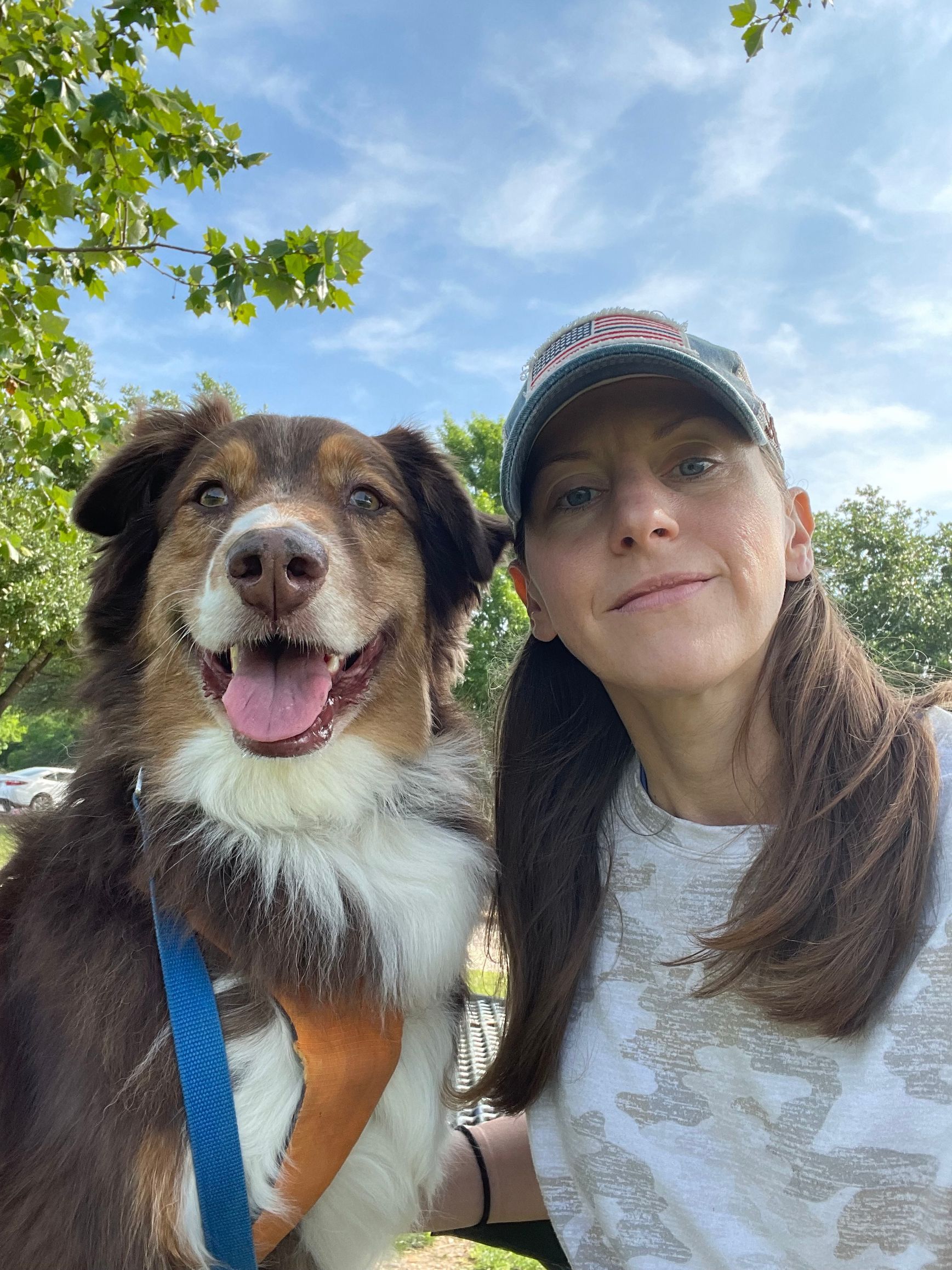 A woman is standing next to a brown and white dog.