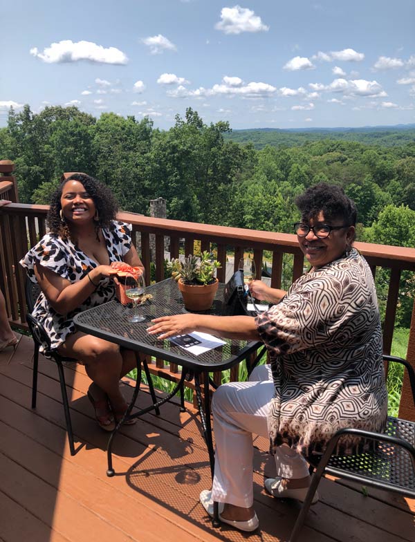 Two women are sitting at a table on a deck.