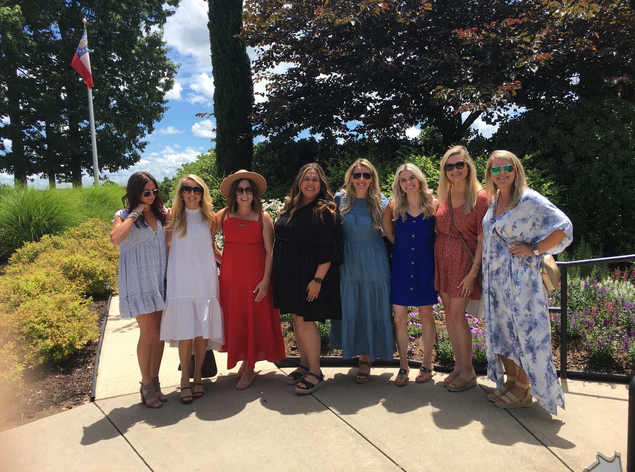 A group of women standing next to each other on a sidewalk.