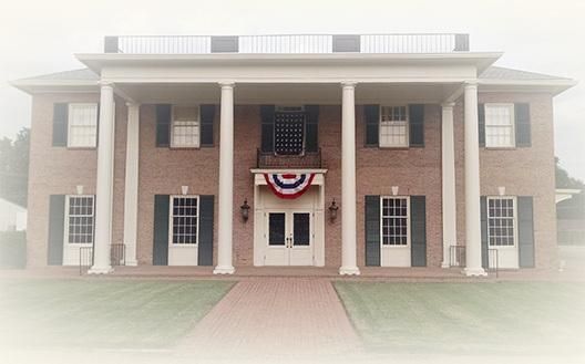 Symmetrical brick building with white columns and patriotic bunting over the entrance