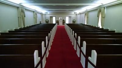 Empty church sanctuary with rows of dark pews and a red carpet aisle leading to the front